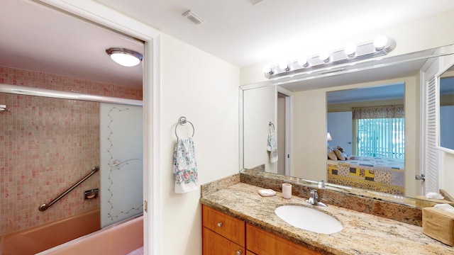 bathroom featuring bath / shower combo with glass door and vanity with extensive cabinet space