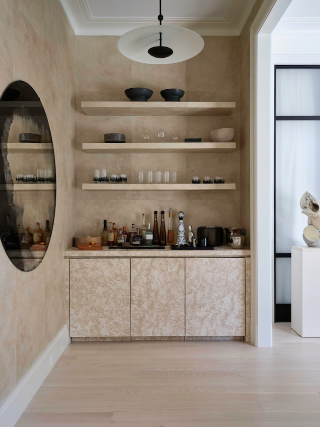 bar featuring crown molding and light hardwood / wood-style flooring