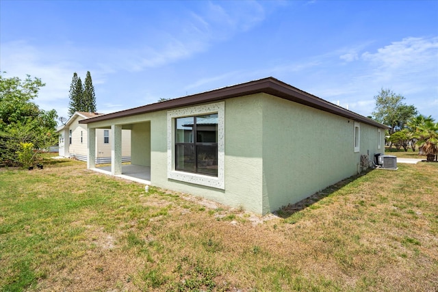 rear view of house with central AC and a yard