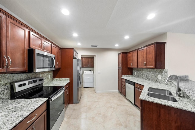 kitchen with stainless steel appliances, washer / dryer, light stone counters, backsplash, and sink