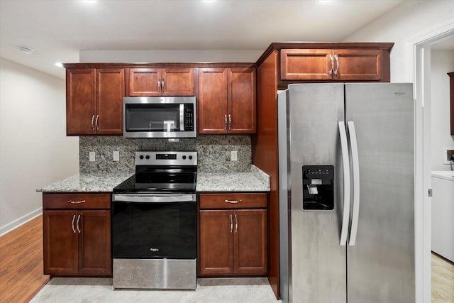 kitchen with stainless steel appliances, washer / dryer, light stone counters, backsplash, and light tile floors