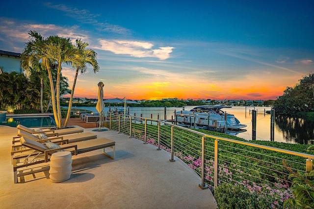 patio terrace at dusk with a boat dock and a water view