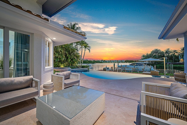 pool at dusk featuring a patio area, a boat dock, and a water view