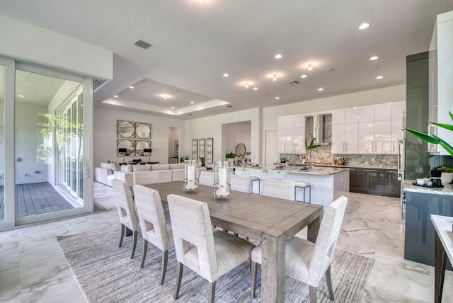 dining room with a raised ceiling and light tile patterned flooring