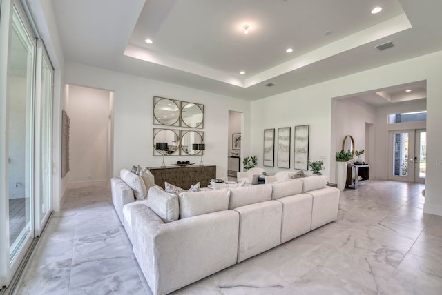 tiled living room with french doors and a raised ceiling