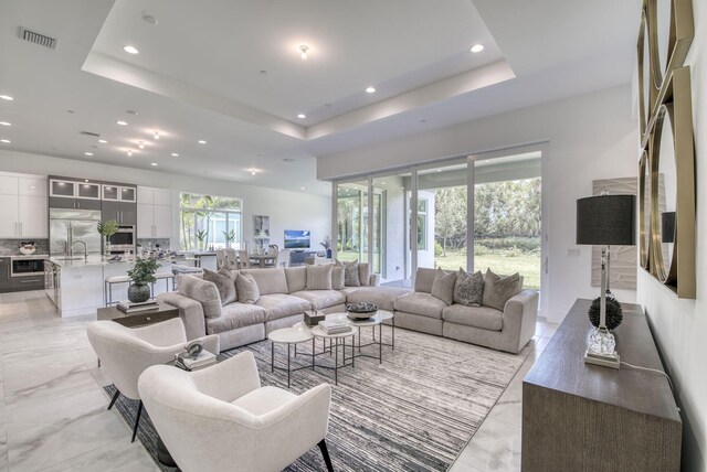 living room with light tile patterned flooring and a raised ceiling