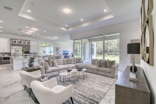 living area with visible vents, a raised ceiling, and recessed lighting