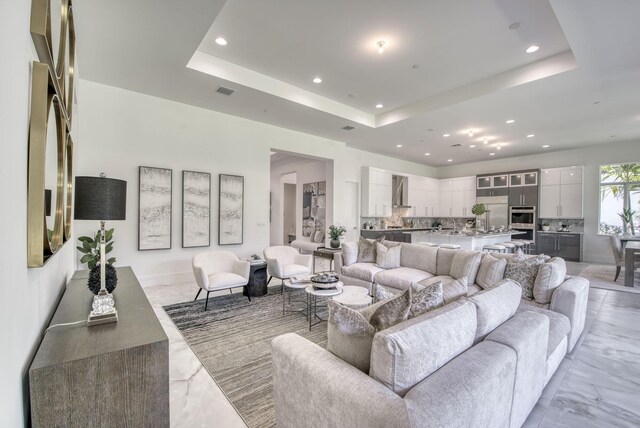 living room with a raised ceiling and light tile patterned floors