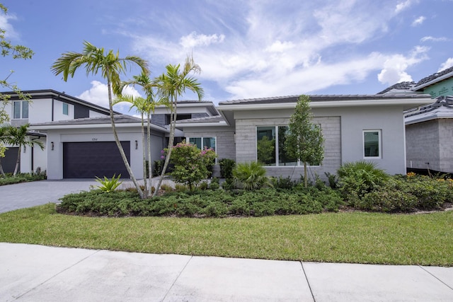 view of front facade with a garage, decorative driveway, and a front lawn