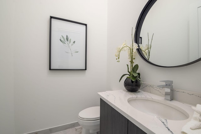 bathroom featuring toilet, vanity, and baseboards