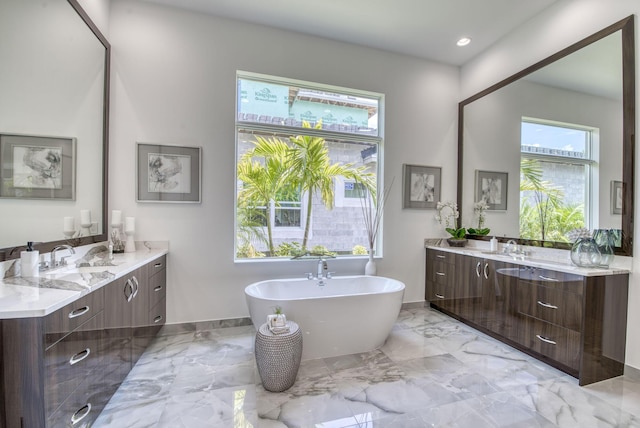 bathroom with marble finish floor, two vanities, a sink, and a soaking tub