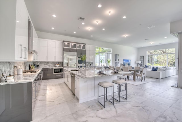 kitchen featuring modern cabinets, white cabinets, a large island with sink, and built in appliances