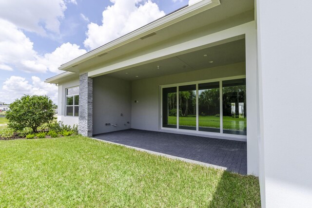 rear view of house featuring a lawn and a patio