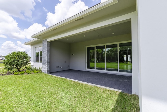 back of property featuring a patio area, a lawn, and stucco siding