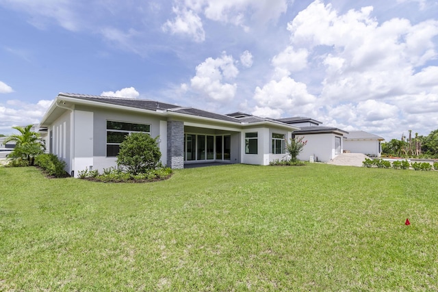 back of property featuring a lawn and stucco siding