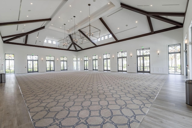 unfurnished living room with high vaulted ceiling, beamed ceiling, and light wood finished floors