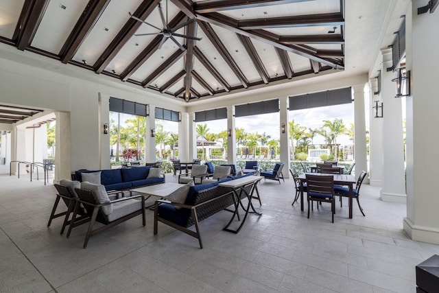 sunroom featuring vaulted ceiling with beams, a ceiling fan, and a healthy amount of sunlight