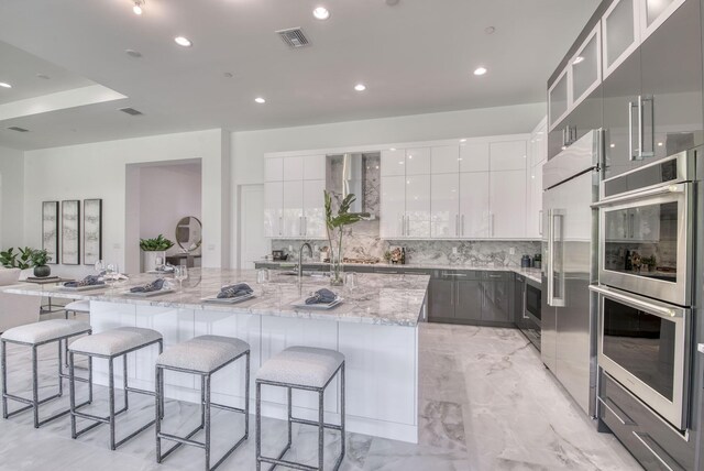 kitchen with appliances with stainless steel finishes, a spacious island, and white cabinetry