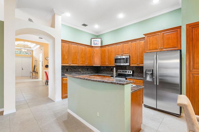 kitchen featuring appliances with stainless steel finishes, tasteful backsplash, dark stone counters, and ornamental molding