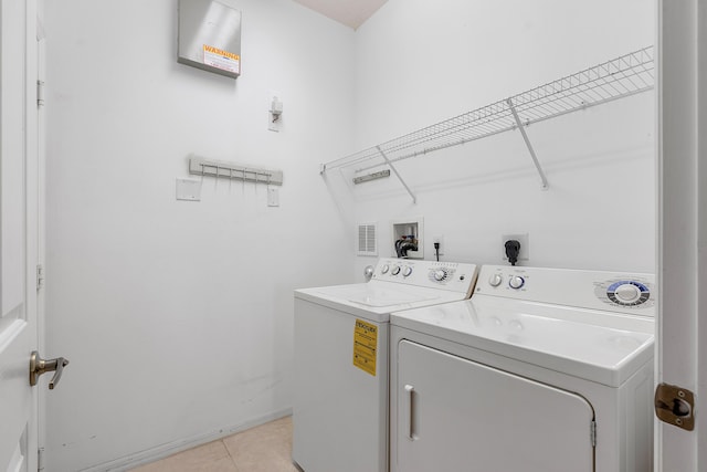 clothes washing area with washer and dryer and light tile patterned floors