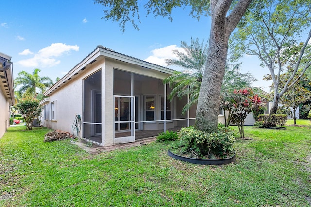 rear view of property featuring a lawn and a sunroom