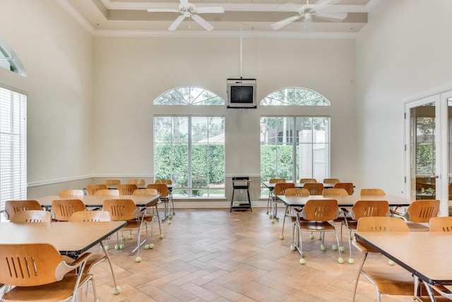 dining area with parquet floors, ceiling fan, ornamental molding, and a towering ceiling