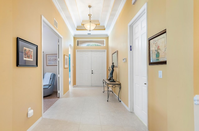 tiled foyer entrance with ornamental molding and a raised ceiling