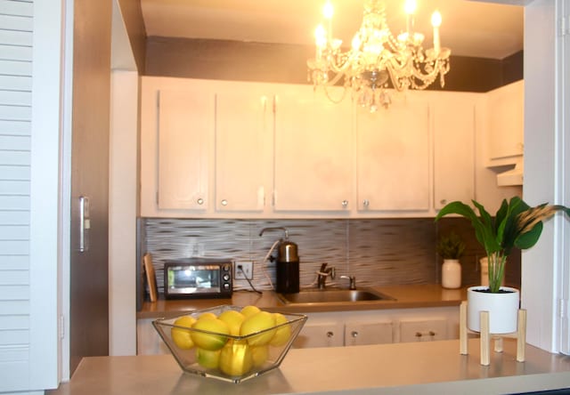 kitchen with a chandelier, tasteful backsplash, hanging light fixtures, and sink