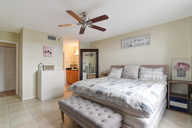 tiled bedroom with ceiling fan, ensuite bathroom, and a textured ceiling