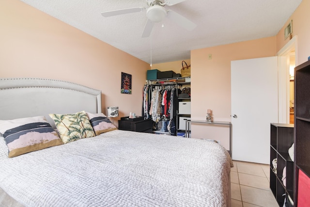 tiled bedroom featuring ceiling fan, a textured ceiling, and a closet