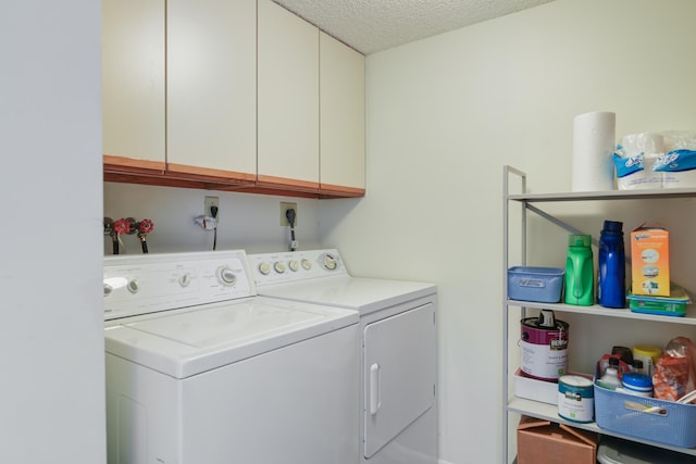 laundry room with washer and dryer, cabinets, and a textured ceiling