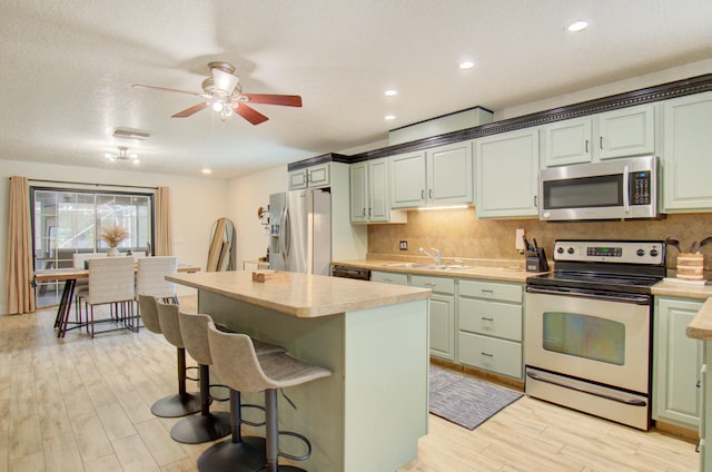 kitchen with light hardwood / wood-style flooring, sink, stainless steel appliances, and a kitchen island