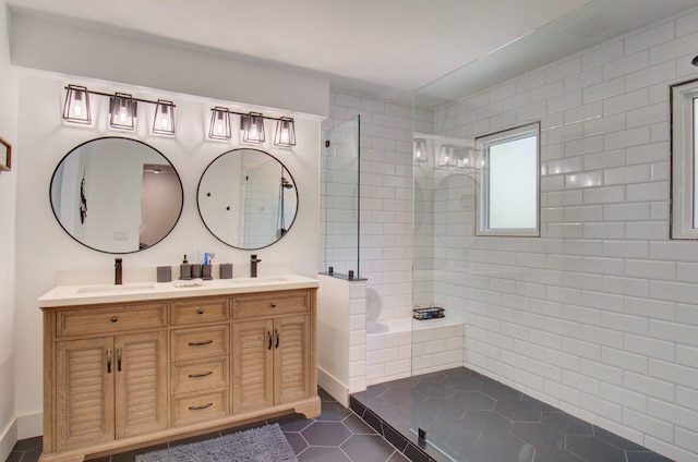 bathroom with tile patterned flooring, a tile shower, and vanity