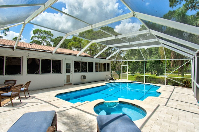 view of swimming pool with glass enclosure, an in ground hot tub, and a patio