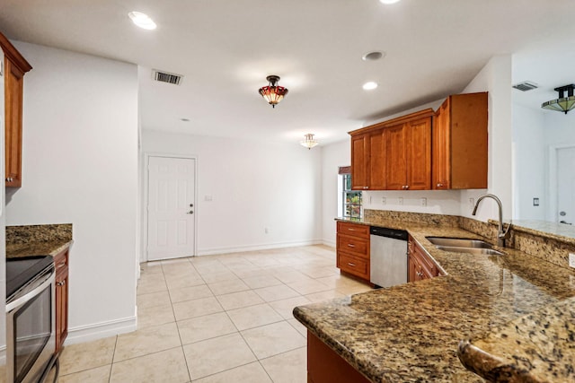 kitchen featuring dark stone countertops, stove, light tile patterned floors, dishwasher, and sink