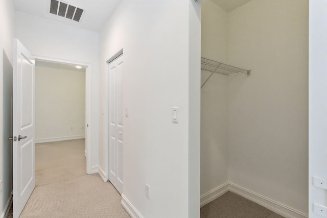 hall featuring visible vents, light colored carpet, and baseboards