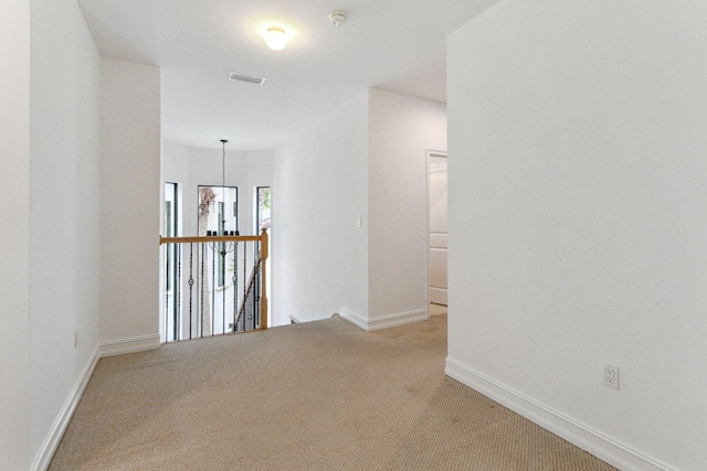 empty room featuring visible vents, light colored carpet, and baseboards