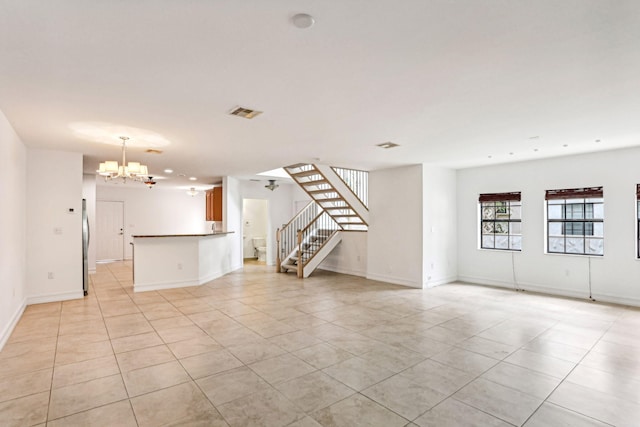 unfurnished living room featuring a notable chandelier and light tile patterned floors