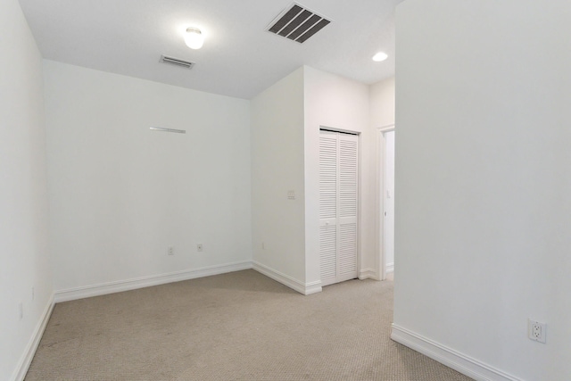 unfurnished room with recessed lighting, light colored carpet, visible vents, and baseboards