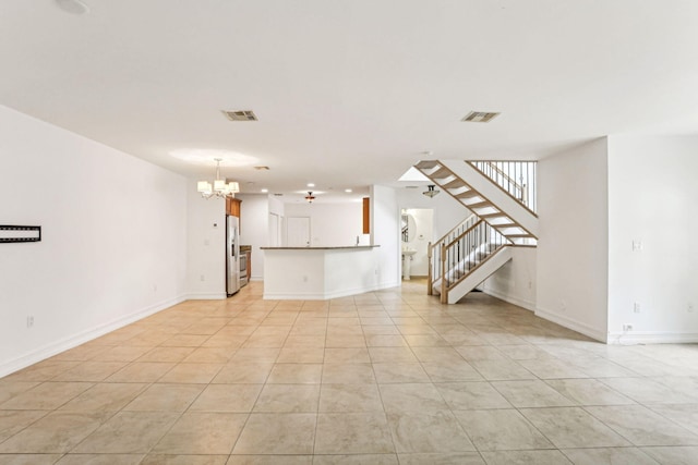 unfurnished living room with visible vents, baseboards, and stairs