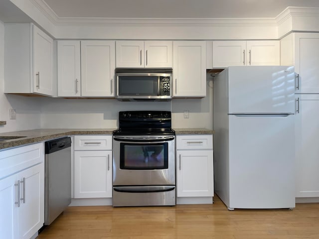 kitchen with appliances with stainless steel finishes, light hardwood / wood-style floors, white cabinets, and ornamental molding