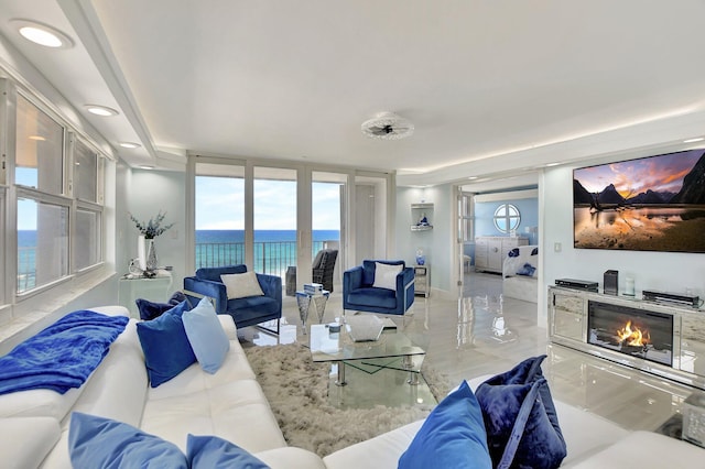 tiled living room with a water view, plenty of natural light, and floor to ceiling windows