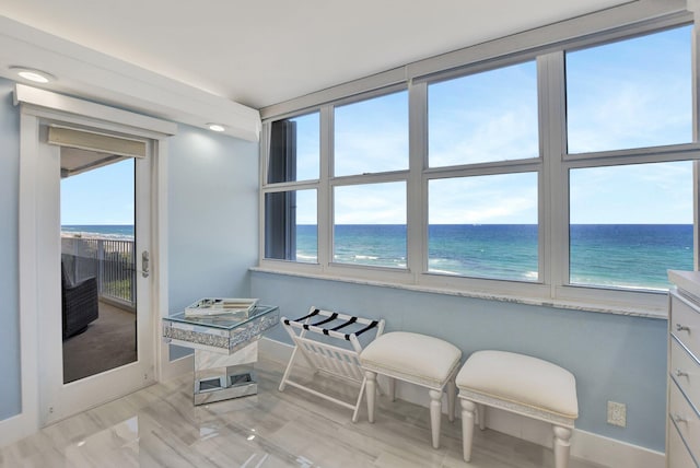 sitting room featuring a water view, light wood-type flooring, and a healthy amount of sunlight