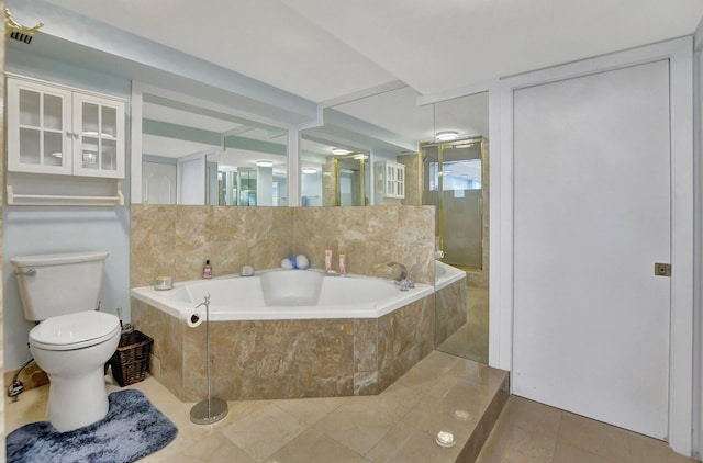 bathroom featuring a relaxing tiled bath, toilet, and tile flooring