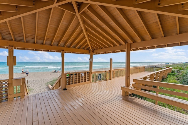 wooden deck featuring a water view and a beach view