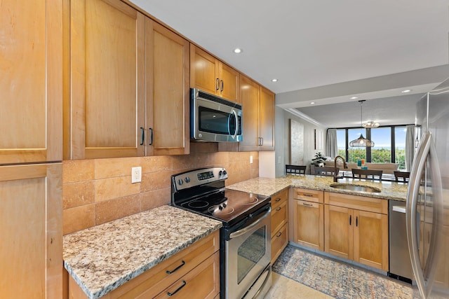 kitchen with kitchen peninsula, stainless steel appliances, backsplash, light stone countertops, and sink