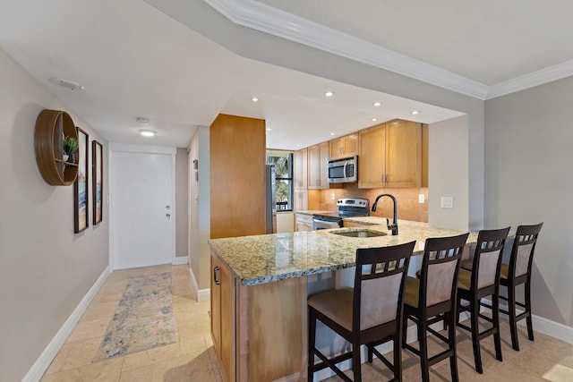 kitchen with kitchen peninsula, stainless steel appliances, light stone countertops, crown molding, and sink