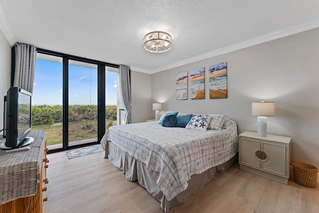 bedroom with ornamental molding, light hardwood / wood-style floors, floor to ceiling windows, and access to exterior