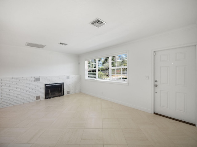 unfurnished living room featuring a fireplace, brick wall, and light tile floors