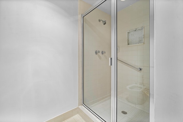 bathroom with a shower with door and tile patterned flooring